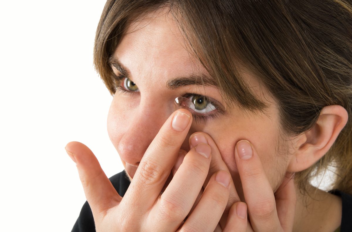 Lentes de contacto Mujer poniéndose una lente de contacto en el ojo izquierdo.