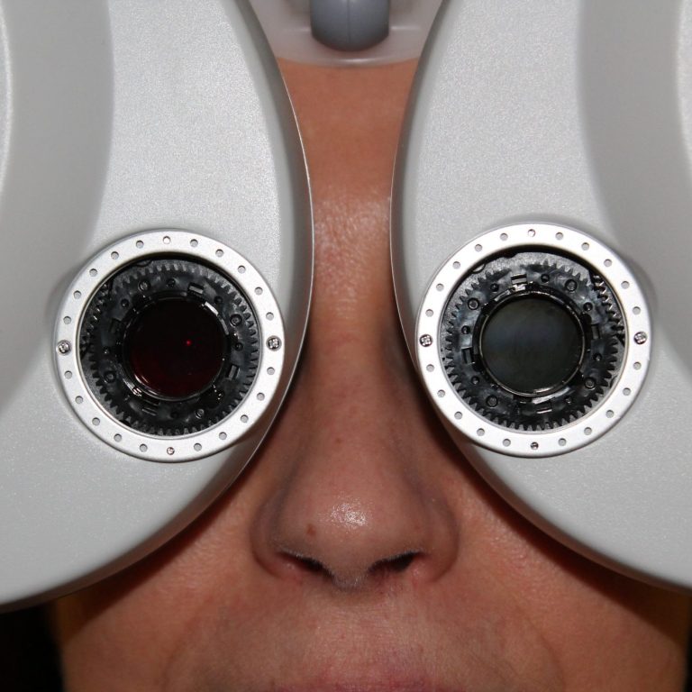 Optometría avanzada Una persona recibiendo un examen visual con un foróptero.